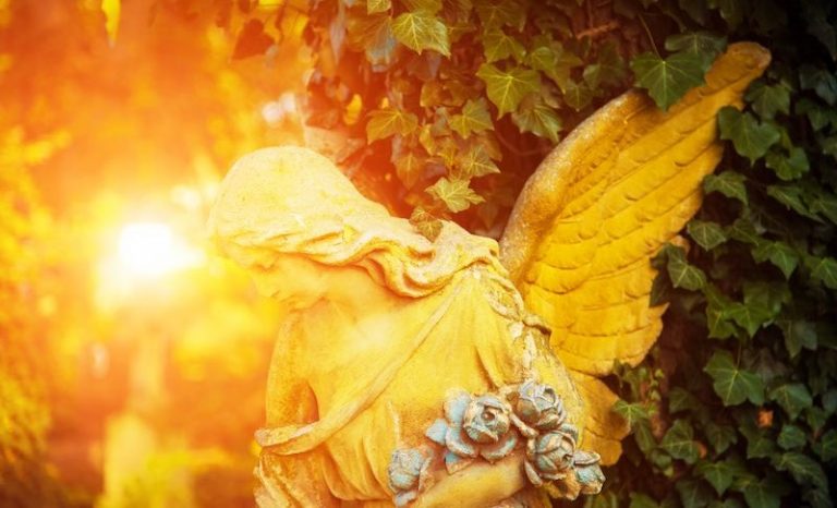 Eine Skulptur eines Engels im goldenen Sonnenlicht vor Bäumen
