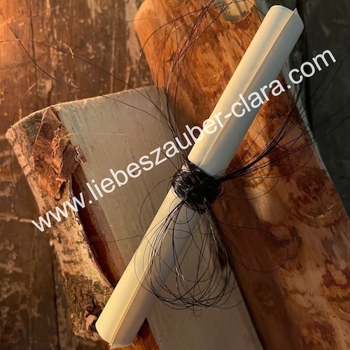 Foto von der Papierrolle, welche mit Pferdehaar umwickelt ist und auf zwei Holzscheiten liegt.